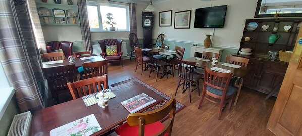 A dining area with wooden furniture, a clock, and a television on the wall. - Sportsmans Valley Hotel (Liskeard)