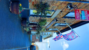 A street view of a building with a sign for 'The Sportsman's Valley Hotel' advertising food, wine, and accommodation. There are flags and a bicycle parked outside.
