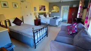 A bedroom with a bed, a sofa, a nightstand, a dresser, and a window with curtains. - Sportsmans Valley Hotel (Liskeard)