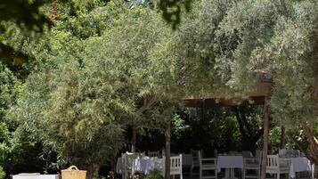 A pool area with a pergola, outdoor seating, and lush greenery.