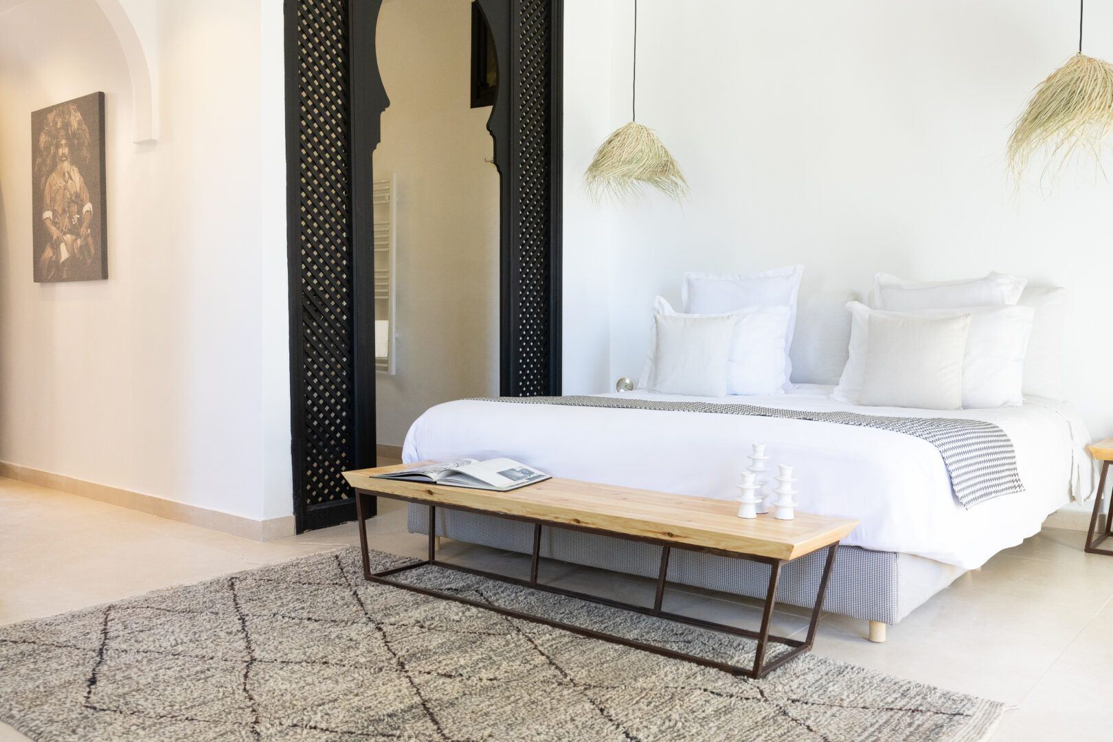 Ein modernes Schlafzimmer mit Bett, Nachttischen, einer Bank und einer Pendelleuchte.