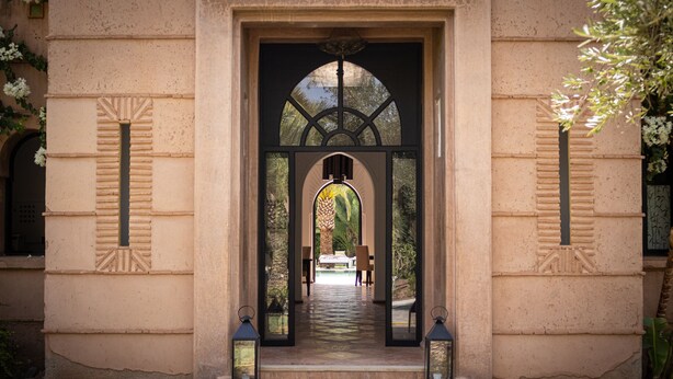 An entrance with a central archway, a pathway leading to a seating area, and lanterns on either side. -  Villa Al Assala Palmeraie - Piscine chauffée (Marrakech)