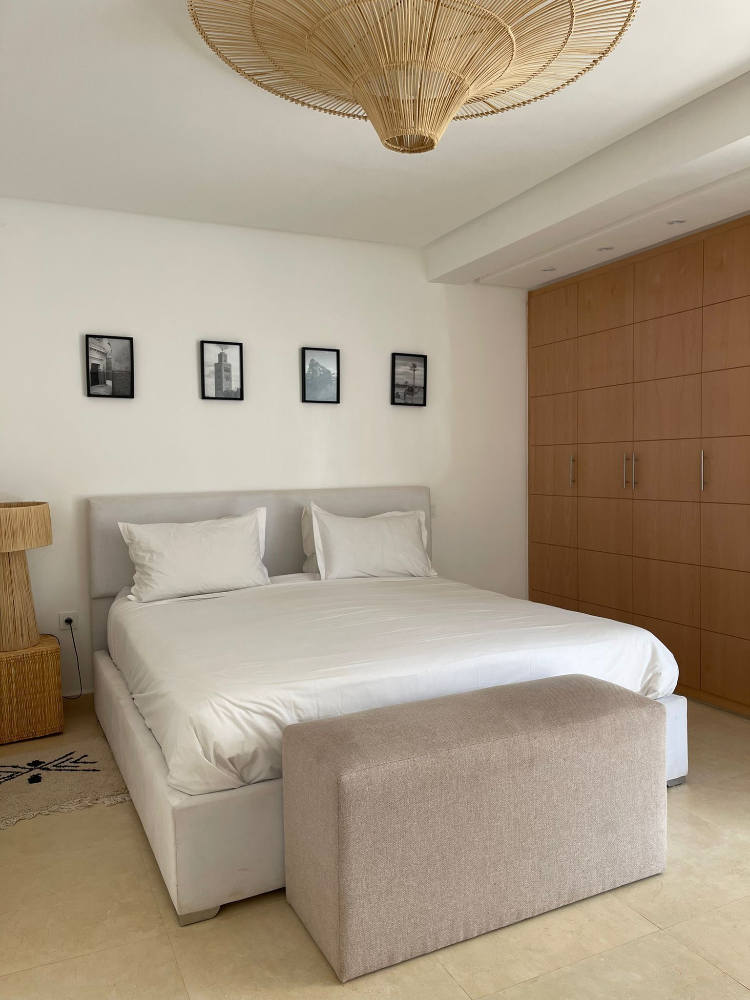 Un dormitorio con cama, lámpara de noche, armario y tres cuadros en la pared.