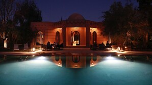 A building with a pool in front, featuring arched doorways and a dome. -  Villa Al Assala Palmeraie - Piscine chauffée (Marrakech)