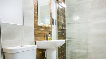 Un baño moderno con inodoro, lavamanos y ducha.