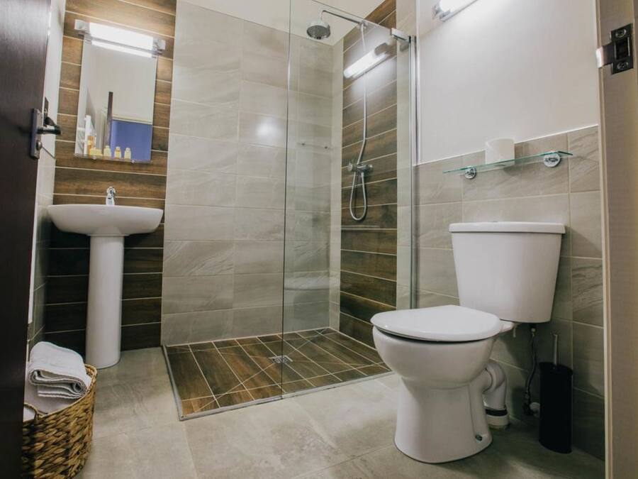 Un baño moderno con ducha de vidrio, lavamanos blanco y retrete.