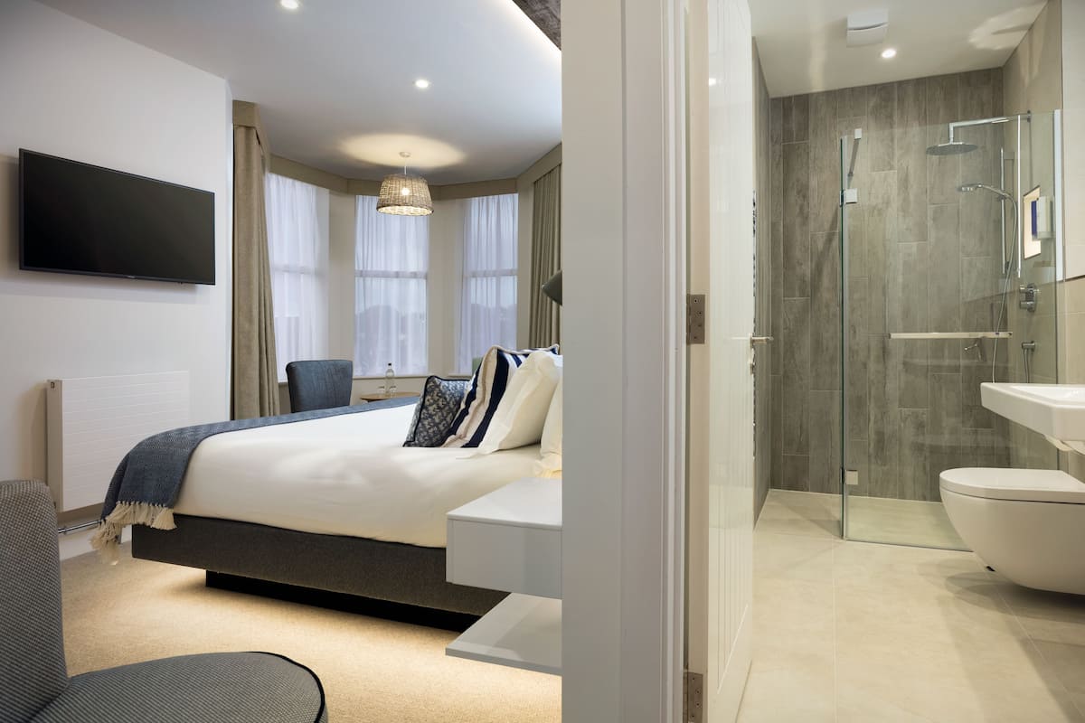 A modern bedroom with a bed, bedside table, and a TV.