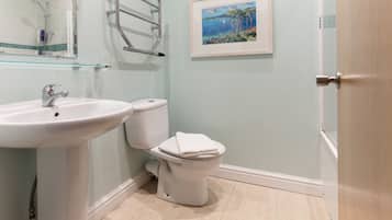 A bathroom with a white sink, toilet, and glass shower enclosure.