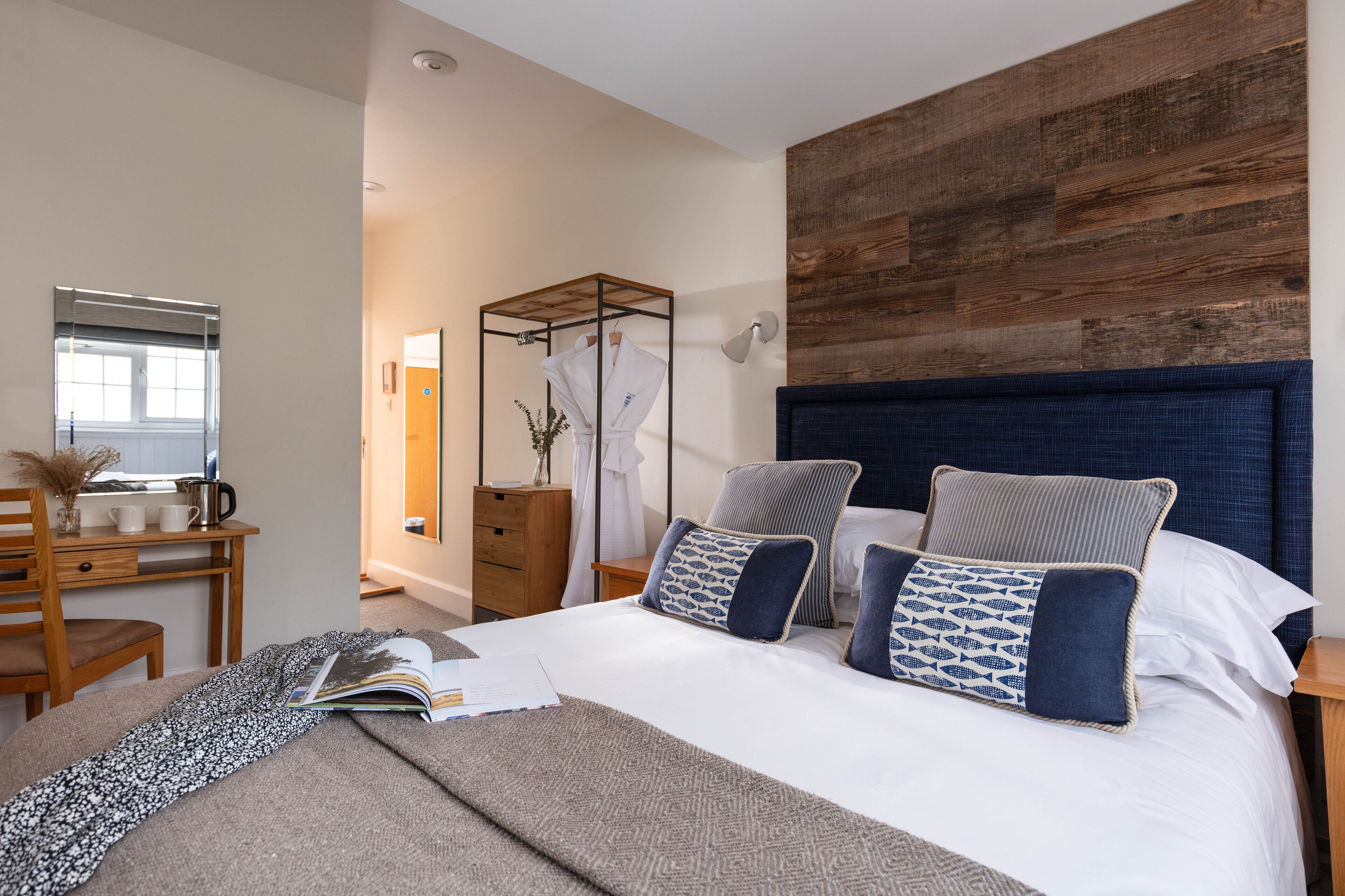 A modern bedroom with a large bed, a wooden headboard, and a desk with a chair.