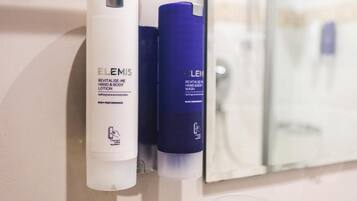 A bathroom with a hand and body lotion dispenser and a mirror.