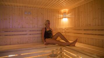 A wooden sauna with benches and a wall-mounted heater.