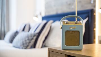 A vintage radio on a bedside table in a modern bedroom with a blue headboard and striped pillows.