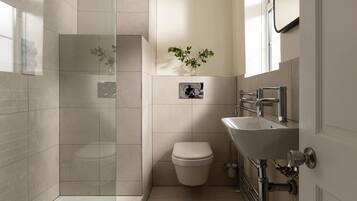 Un baño moderno con cabina de ducha de vidrio, inodoro y lavabo con espejo.