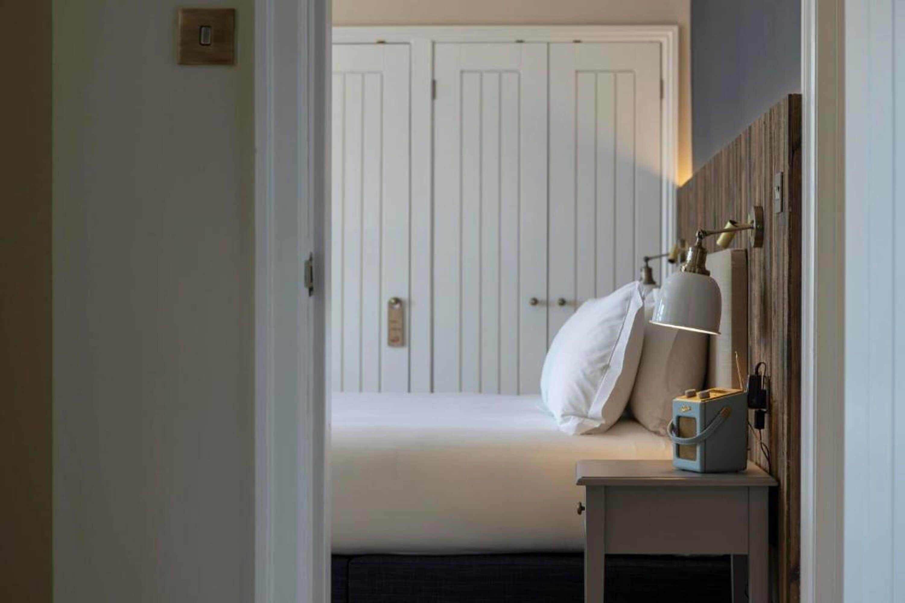 Quarto com cama, mesa de cabeceira, luminária e guarda-roupa.