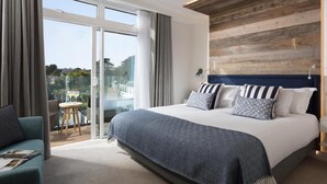Un dormitorio moderno con una cama grande, un revestimiento de pared de madera y un balcón con vistas.