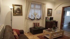 A cozy living room with a brown sofa, a glass coffee table, and a wooden floor.