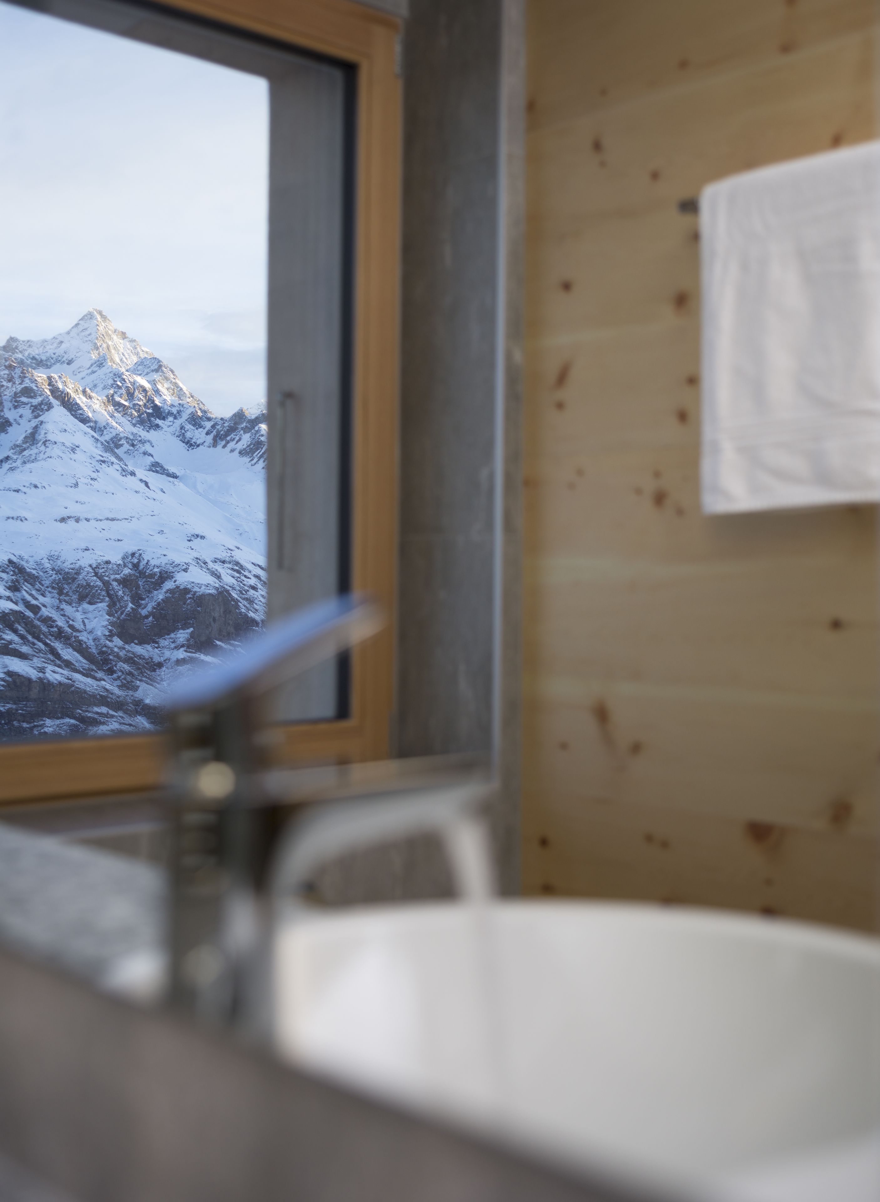 A bathroom with a view of snow-covered mountains through a window.
