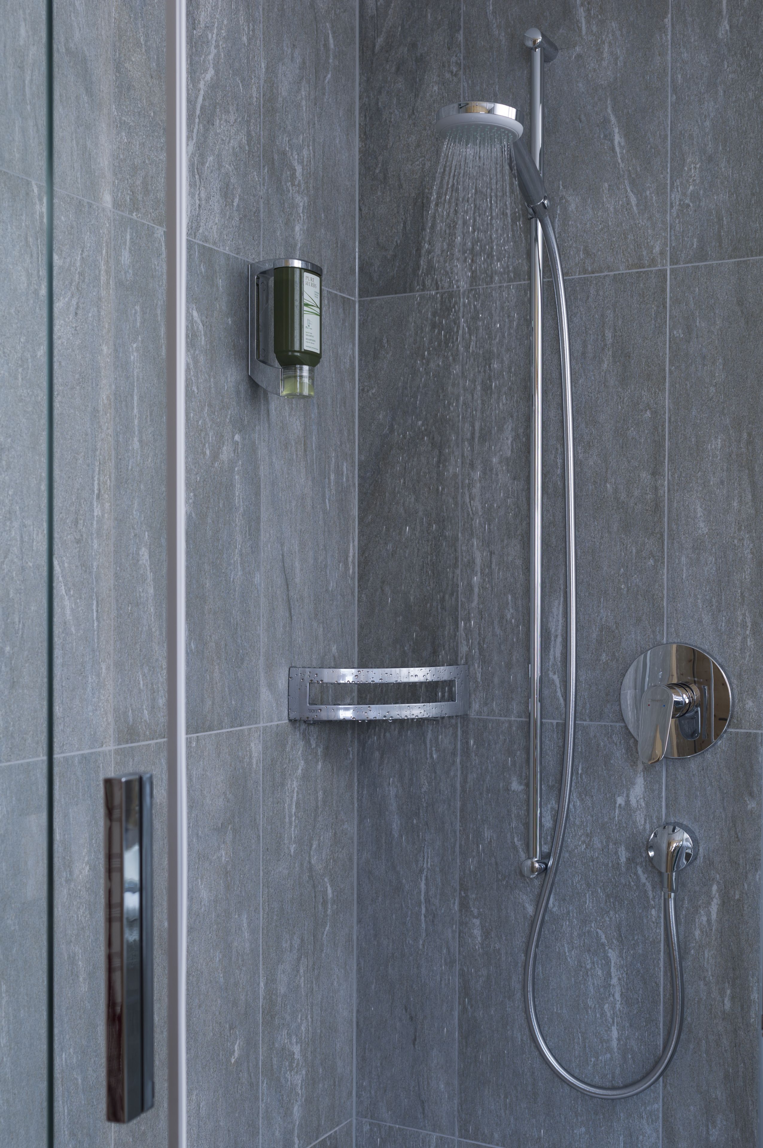 A modern shower with a handheld showerhead and a wall-mounted control panel.