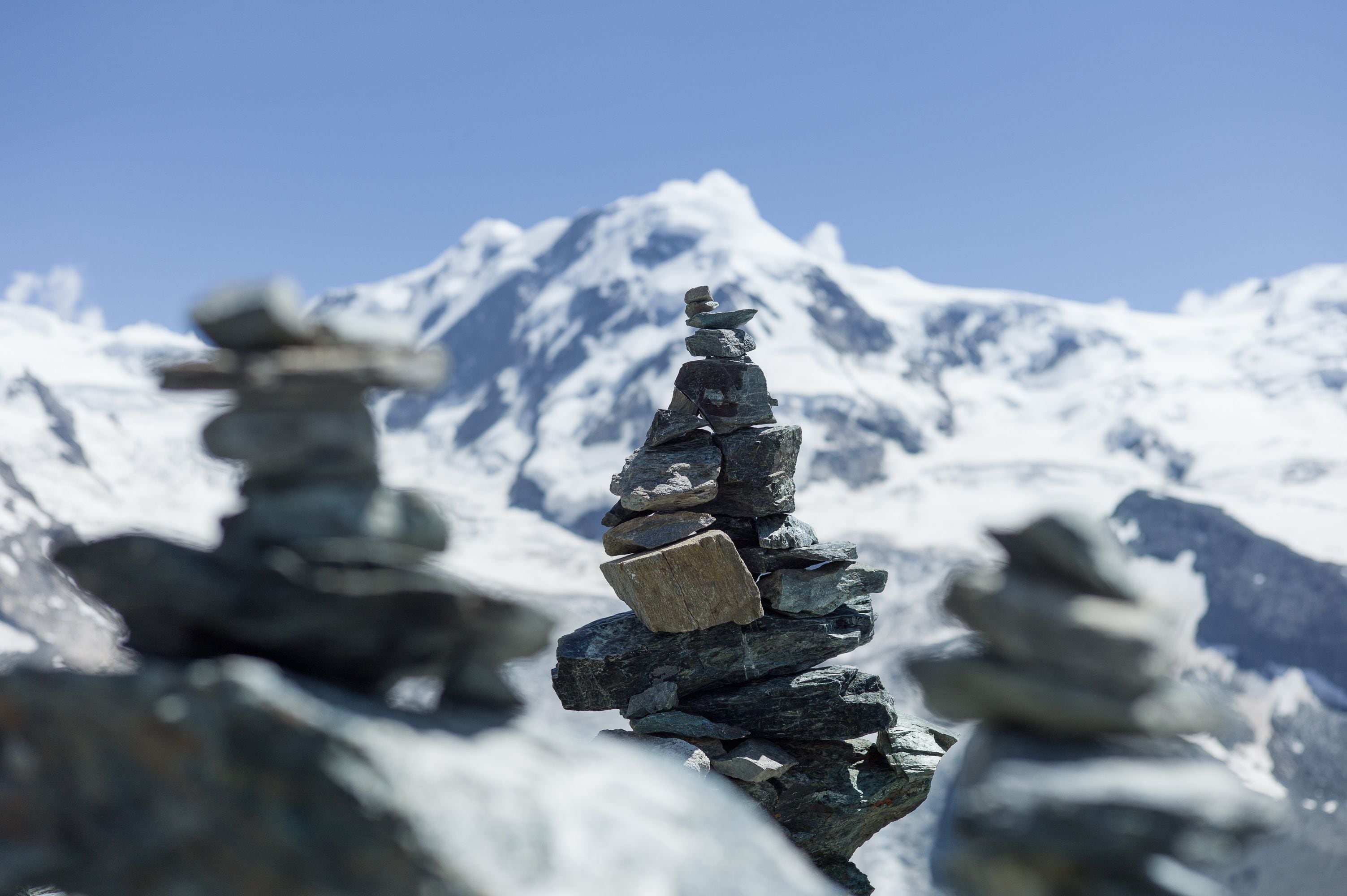 A stack of rocks in a snowy landscape with a mountain in the background.