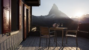 Una terraza de madera con una mesa y sillas, con vista a una montaña.