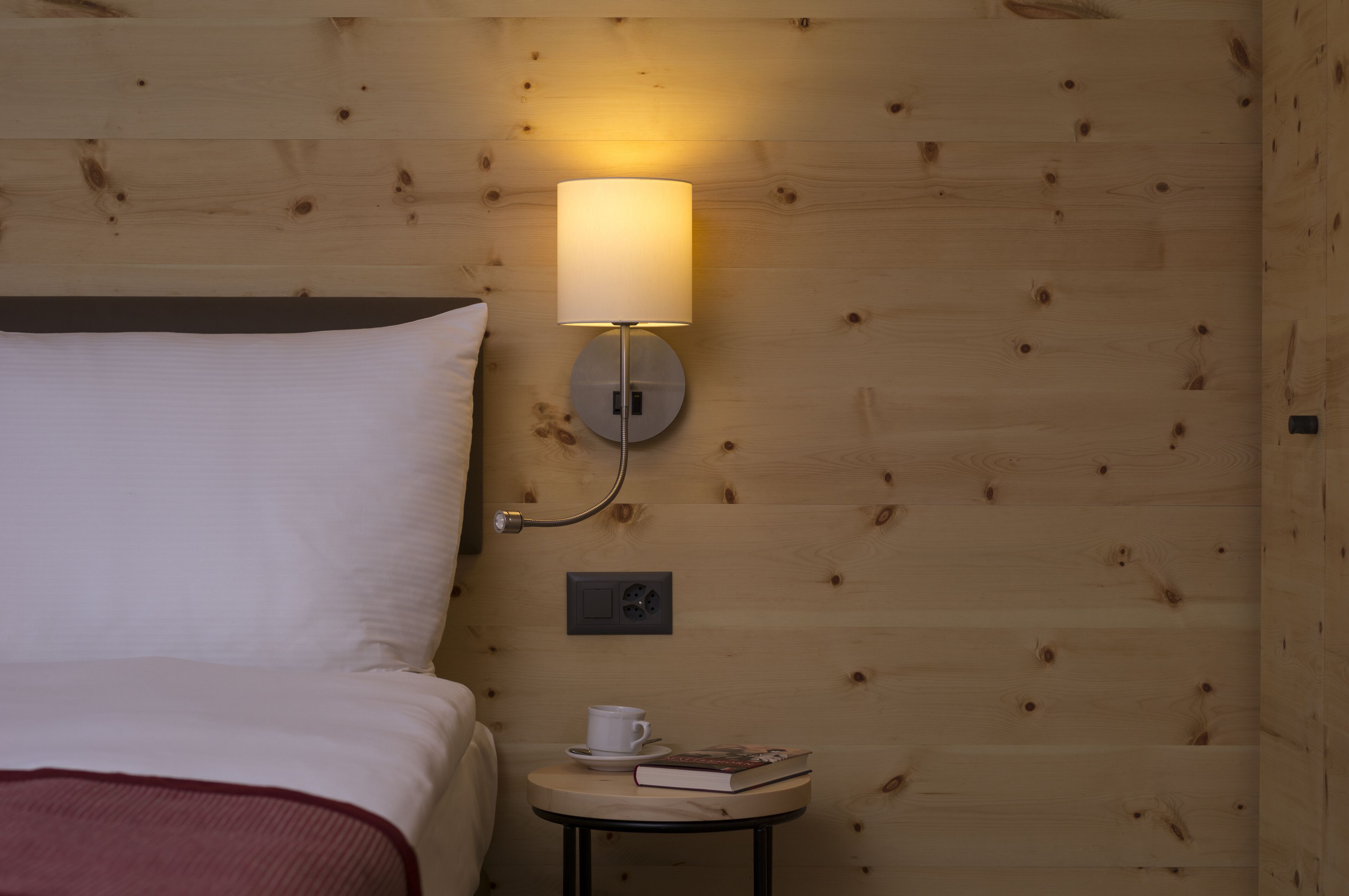 A wooden wall with a round table, a lamp, and a cup on the table.