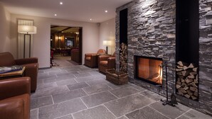 Una sala moderna con chimenea de piedra, sofás de cuero y un área de comedor al fondo.