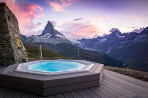 A hot tub on a wooden deck with a mountain view. - Riffelhaus 1853 (Zermatt)