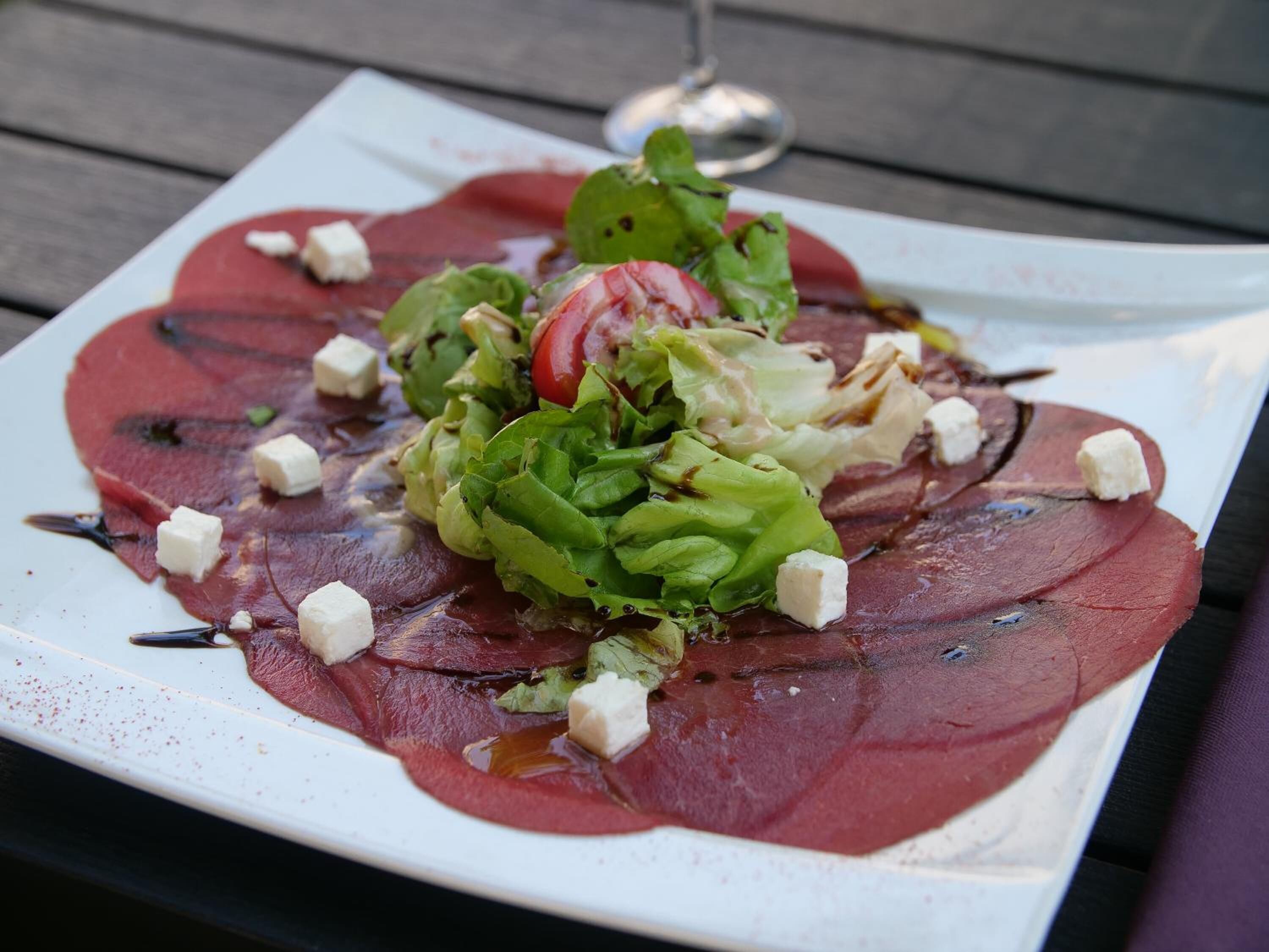 A plate of food with a glass of wine on a wooden table.