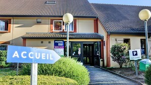 Een hotelentree met een bord waarop "HOTEL inn RESTO NOVO" staat, en een bord met "ACCUEIL" en "NON GARDÉ".