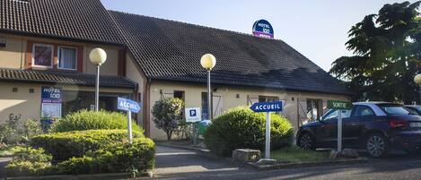A hotel with a sign indicating 'HOTEL 100 RESTO NOVO' and 'ACCUEIL' and 'SORTIE' signs.