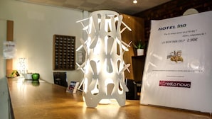 Een hotel receptie met een moderne witte lamp en een promotiemeter voor 'Hotel Inn' met een 'La Box' ervaring voor 2,90 euro.