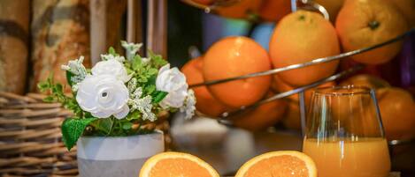 A tray with oranges, a glass of orange juice, and a floral arrangement.
