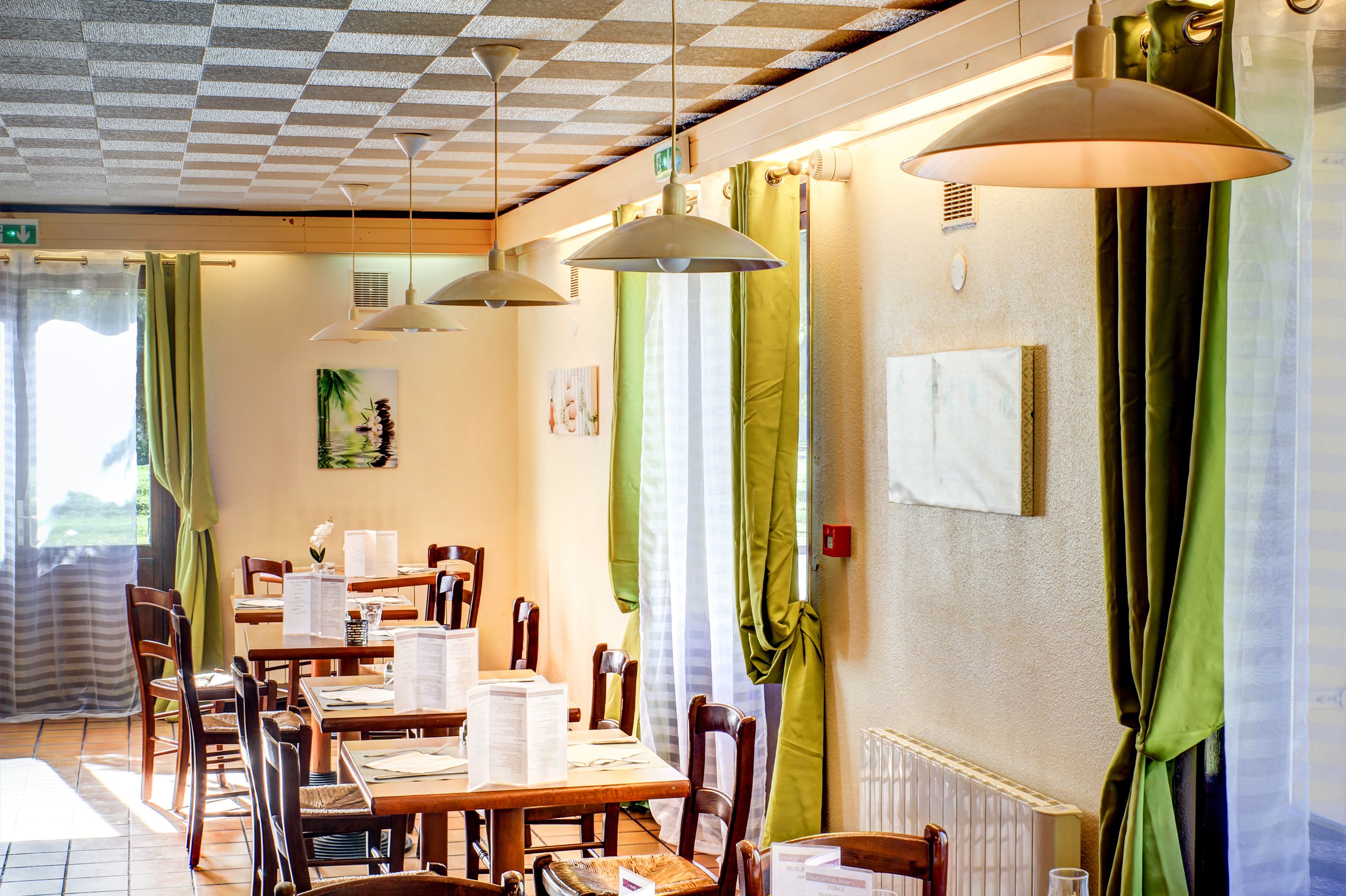 A dining area with tables, chairs, and hanging pendant lights.