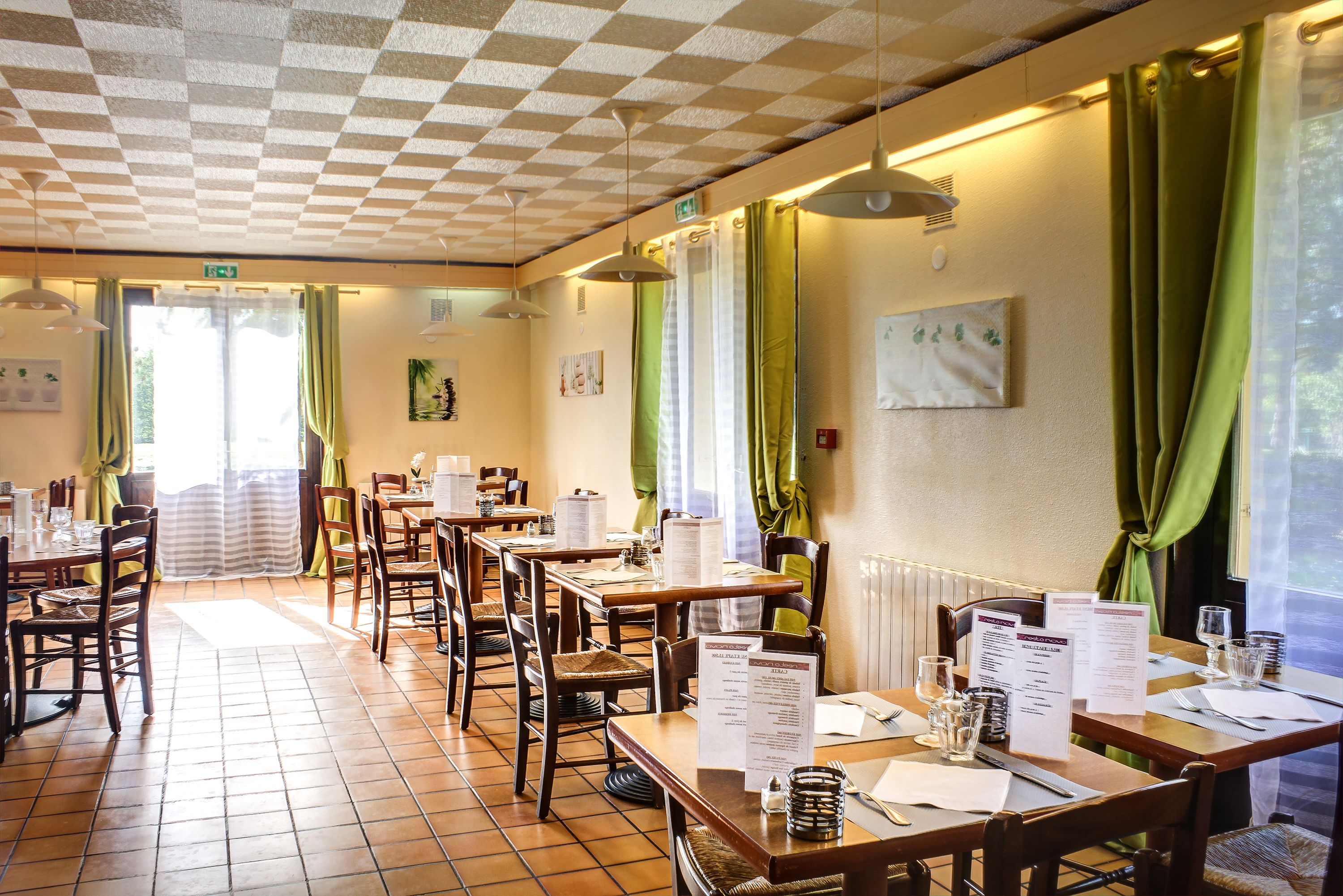 A restaurant with wooden tables and chairs, menus, and a tiled floor.
