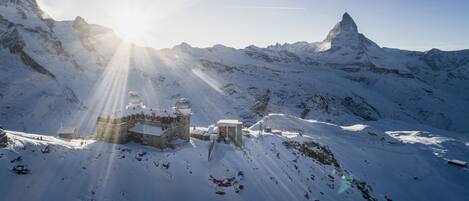 A snow-covered mountain with a building featuring a dome and a smaller structure.