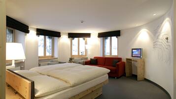 Una habitación de hotel moderna con una cama grande, un sofá rojo, un escritorio con computadora y una pared con diseño original.