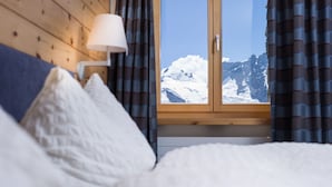 A bedroom with a view of snow-capped mountains through a window. - 3100 Kulmhotel Gornergrat (Zermatt)