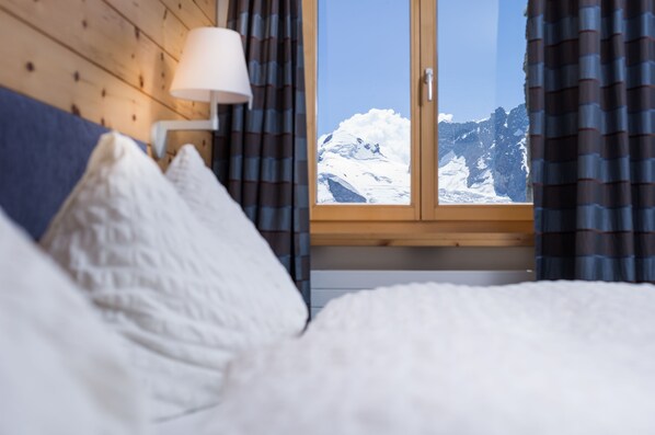 Un dormitorio con vista a montañas nevadas a través de una ventana.