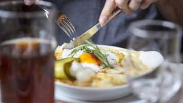 Una persona cortando comida con un tenedor y un cuchillo en un plato.