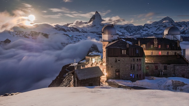 A mountain lodge with a large observatory dome, snow-covered peaks, and a clear sky. - 3100 Kulmhotel Gornergrat (Zermatt)