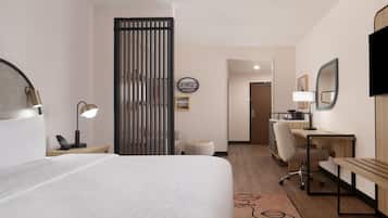 Een hotelkamer met een bed, bureau, stoel, lamp en een schuifdeur.
