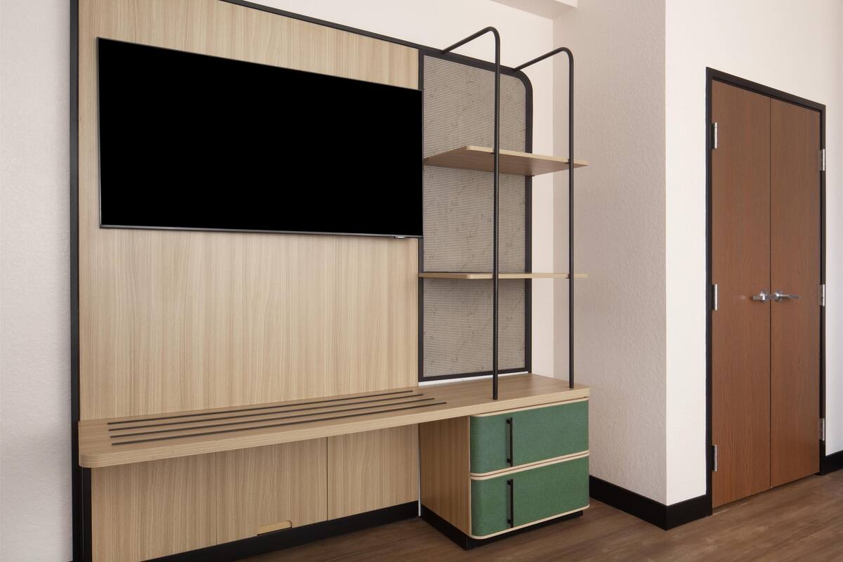 Ein Zimmer mit integriertem Fernseher, einer Holzkabine mit Schubladen und einer Tür.