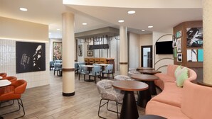 A modern interior with a dining area, sofas, and a TV mounted on the wall.