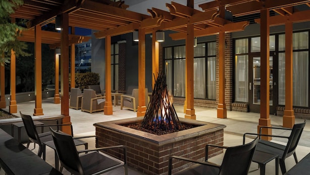 An outdoor seating area with a fire feature, wooden pergolas, and brick flooring.