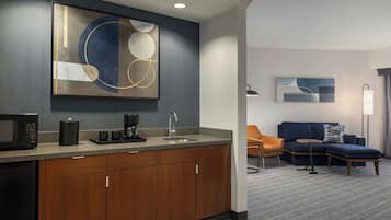 A modern hotel room with a kitchenette, a sofa, and a coffee table.