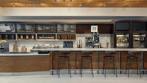 A modern bar area with a wooden ceiling, bar stools, a menu board, and a Starbucks sign.