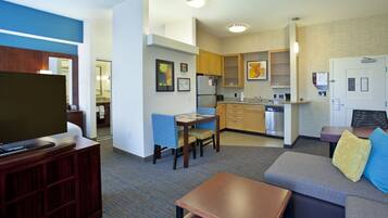 A compact living space with a kitchenette, a dining area, and a seating area with a sofa and a TV stand.