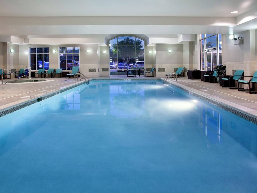 Una piscina interior con sillones de descanso y vista al estacionamiento.