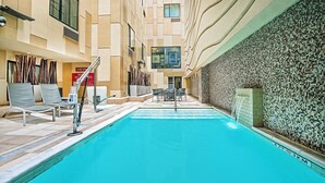 Una piscina con sillones reclinables y una pared de azulejos.