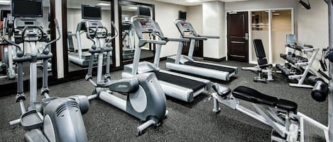 Une salle de sport équipée de tapis de course, d’appareils de musculation et de poids libres.